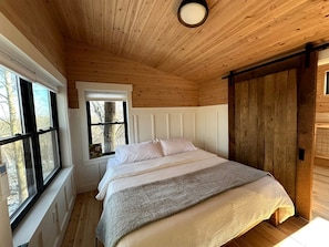 Une chambre à coucher avec un lit, une fenêtre et un plafond en bois.