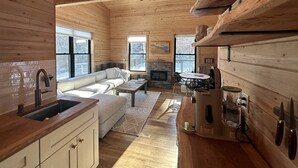 A wooden interior with a kitchen, dining area, and a fireplace.