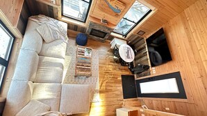 A compact cabin with a sofa, a small table, a television, and a fireplace.