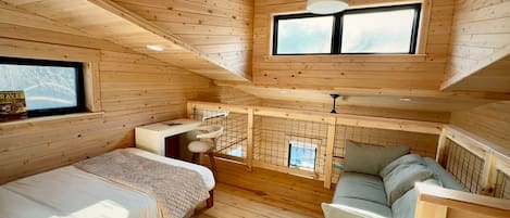 Una cabaña de madera con habitación en altillo, comedor y sala de estar.