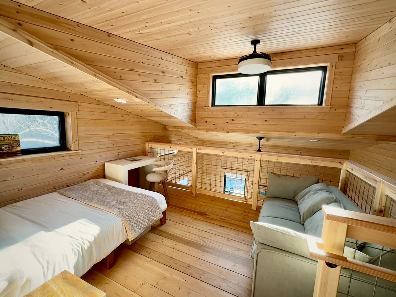 A wooden cabin with a loft bedroom, a dining area, and a seating area.