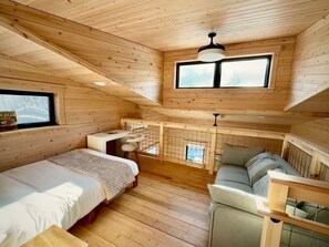 Una cabaña de madera con habitación en altillo, comedor y sala de estar.