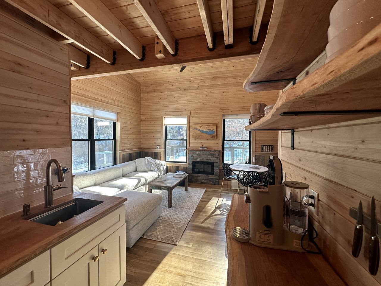 A wooden interior with a kitchen, dining area, and a fireplace.