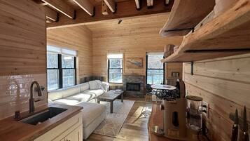 A wooden interior with a kitchen, dining area, and a fireplace.