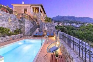 A stone building with a pool, a chair, and a view of the mountains. - Acrothea Villa Heated Pool (Kournas)