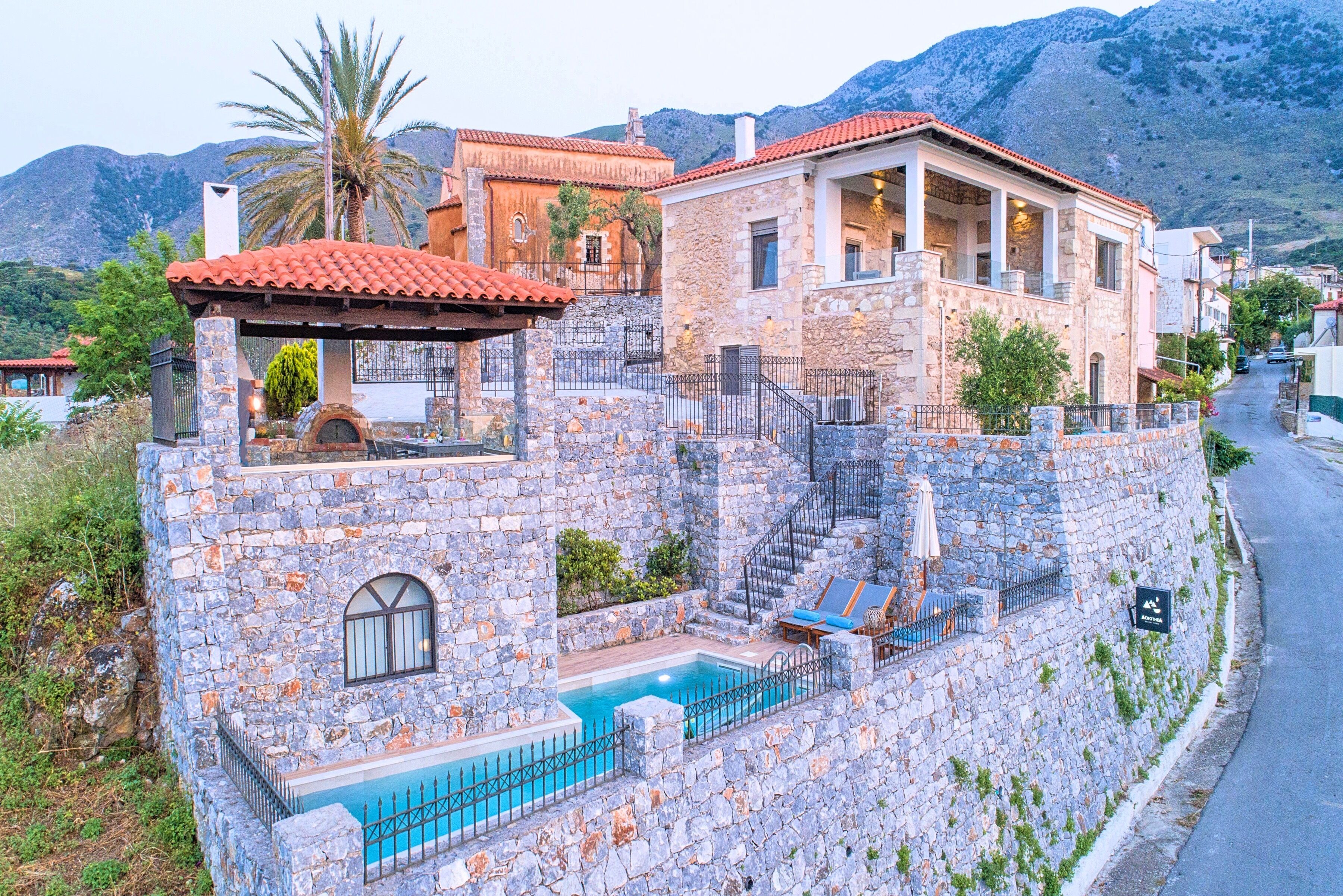 A stone-walled building with a pool, a staircase, and a view of the surrounding landscape.