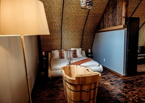A bedroom with a wooden bathtub, a bed with a striped blanket, and a blue wall. - Incredible Secluded Barn with Hot-tub and Petting Zoo in Sugar Grove, North Carolina (Sugar Grove)