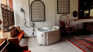 Et værelse med jacuzzi, en træbænk, en rød stol og en tapetvæg.