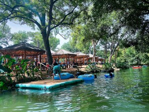 Zona ribereña con plataformas flotantes y estructuras de techo de paja.