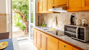 Una cocina moderna con armarios de madera, un microondas integrado y una ventana con vistas a un jardín.
