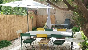 Un patio con una mesa, sillas, una sombrilla y una parrilla.
