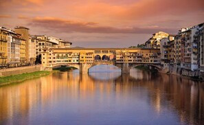 A historic bridge over a calm river with buildings on either side. - [Liberty Square] Historic Apt for 8 - 4BR, Private Courtyard, 10 min to Duomo (Firenze)