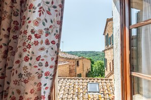 Una ventana con vista a un edificio tradicional de techo con tejas y una ventana pequeña.