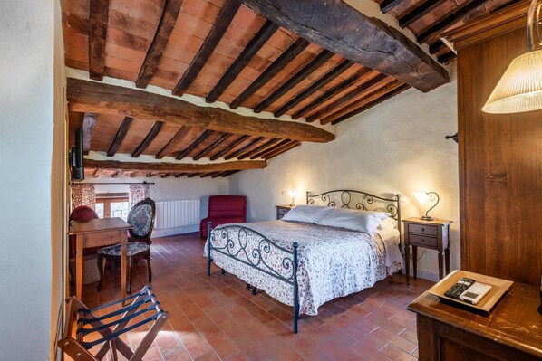 Ein Schlafzimmer mit Bett, Stuhl, Tisch, Nachttisch und Lampe.