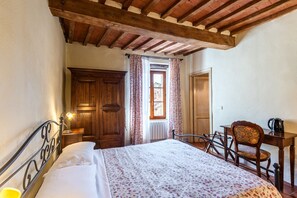 A bedroom with a bed, wooden wardrobe, a desk with a chair, and a window with curtains. - Locanda di Montisi Contrada Room among the Hills of Montalcino (Montisi)