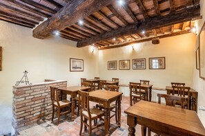 A dining area with wooden tables and chairs, a brick fireplace, and framed artwork on the walls. - Locanda di Montisi San Martino Room among Montalcino Hills (Montisi)