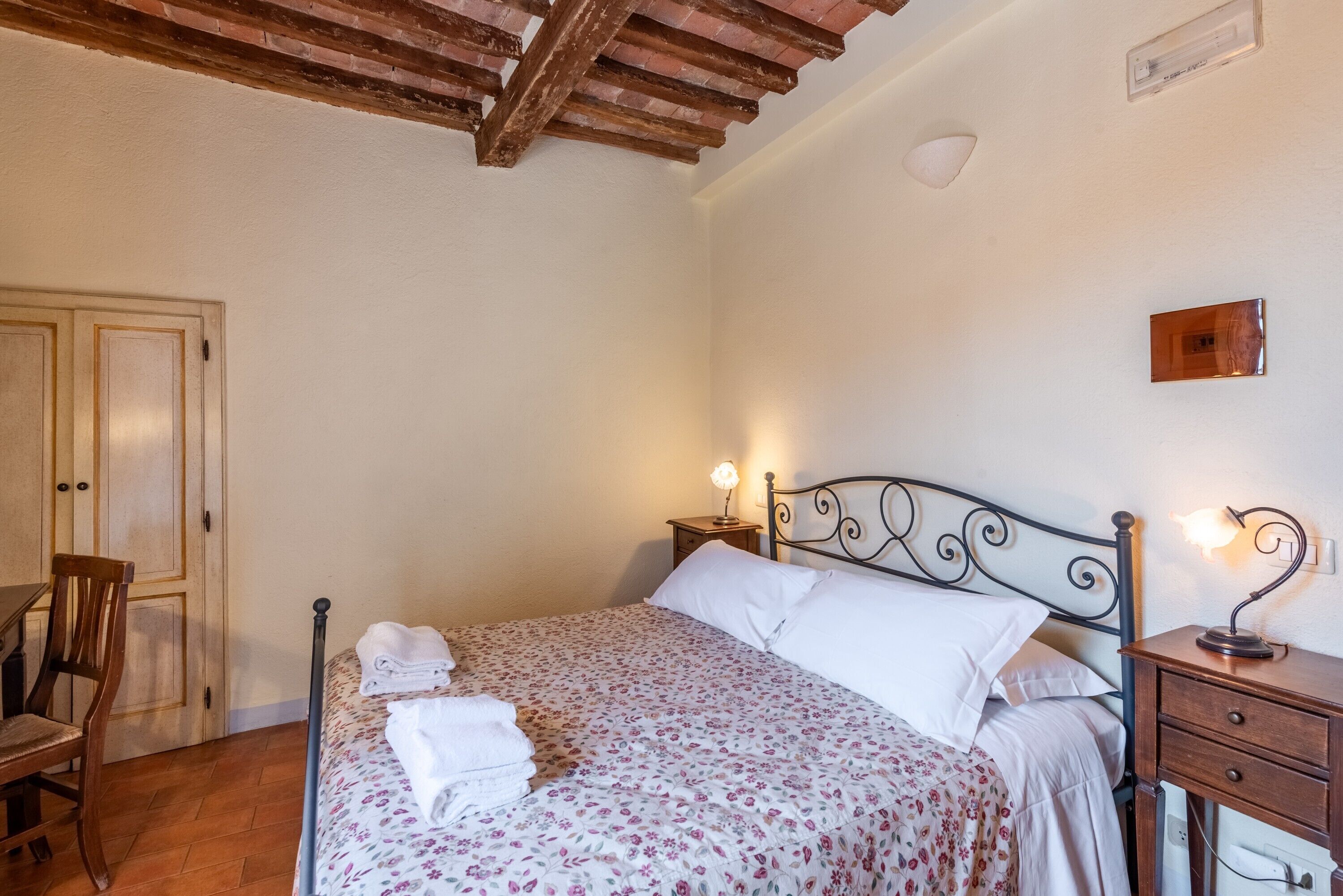 Une chambre à coucher avec un lit, des tables de chevet, une chaise et un plafond en bois.