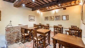 A dining area with wooden tables and chairs, a brick fireplace, and framed artwork on the walls.