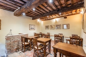 A dining area with wooden tables and chairs, a brick fireplace, and framed artwork on the walls. - Locanda di Montisi Piazza Room between the hills of Montalcino (Montisi)