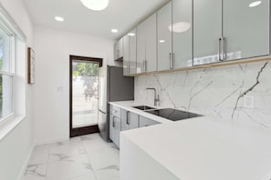 A modern kitchen with white cabinets, a marble backsplash, and a large island.