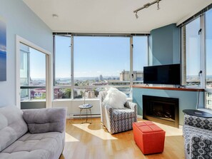 Ein modernes Wohnzimmer mit Sofa, Hocker und Sessel, einem Kamin und einem Fernseher auf einem Lowboard.