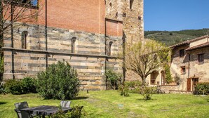 A stone building with a tower, a grassy courtyard, and a small outdoor seating area. - Borgo San Jacopo - Il Cipressino (Vicopisano)