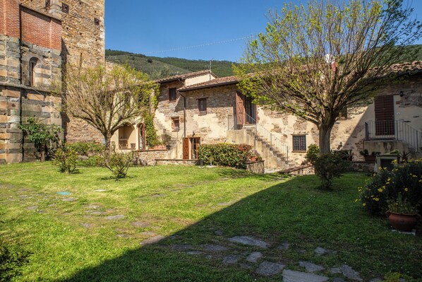 A courtyard with stone buildings, a tree, and a clear sky. - Borgo San Jacopo - Il Cipressino (Vicopisano)