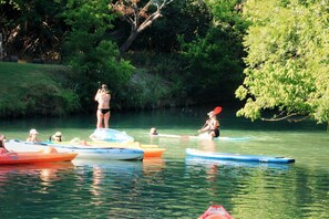 Un grup de persones fent piragüisme en un riu tranquil envoltat de vegetació.