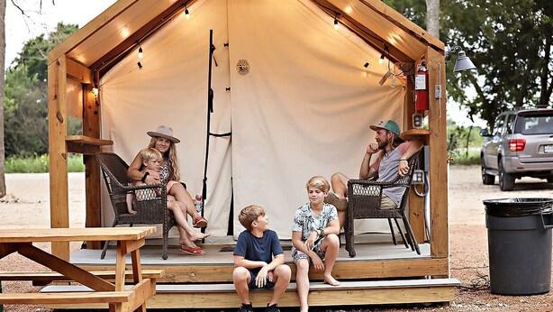 A wooden tent with a covered porch, seating, and a fire extinguisher.