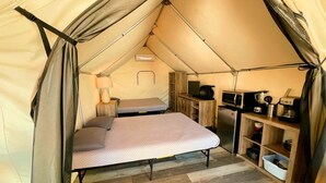 A tent with a bed, a kitchenette, and a small table.