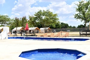 A swimming pool with lounge chairs and a barbecue grill.