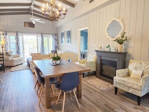 A spacious living room with a wooden dining table, comfortable seating, a fireplace, and a large mirror on the wall. - Beach Haven South - Minutes from the Beach, Second Row North Litchfield (Pawleys Island)