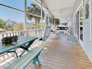 A covered porch with wooden benches, a table with a plant, and a view of the neighborhood. - Beach Haven South - Minutes from the Beach, Second Row North Litchfield (Pawleys Island)