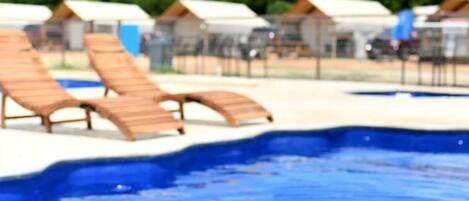 Piscina com espreguiçadeiras e um flutuador rosa.