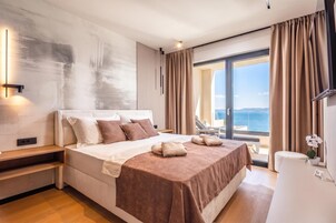Habitación de hotel moderna con una cama grande, vista al mar y un balcón.