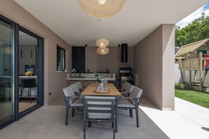 Une cuisine moderne avec un coin repas, une grande fenêtre et un barbecue intégré.