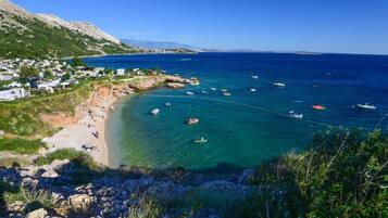 A coastal area with clear waters, boats, and a small settlement with houses and a beach.