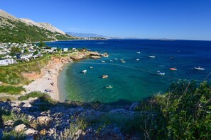 A coastal area with clear waters, boats, and a small settlement with houses and a beach.
