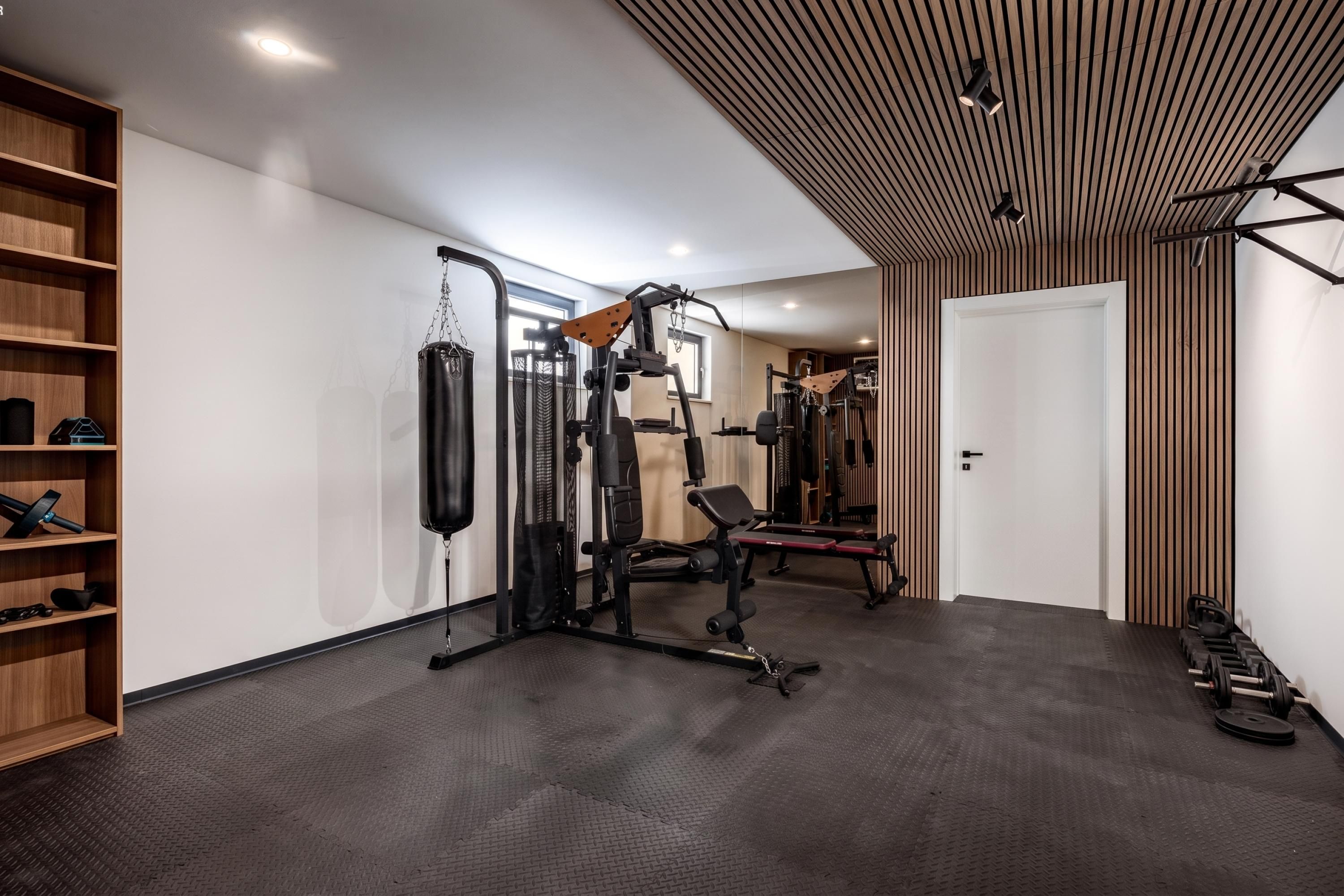 Un gimnasio con equipo de ejercicio, un saco de boxeo y una banca para pesas.
