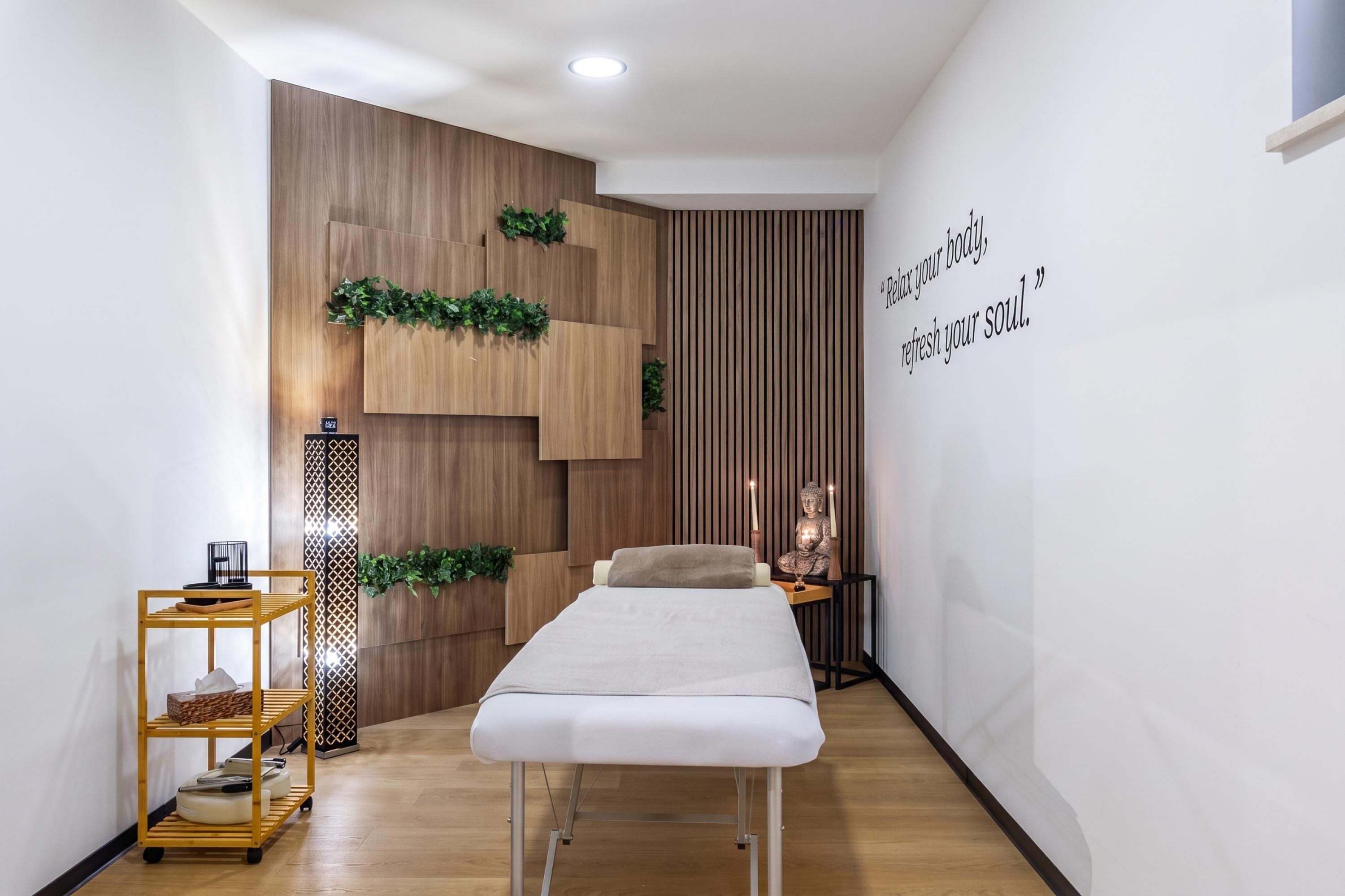 Una habitación moderna con pared de madera, cama, una mesita con velas y una pared con una cita.