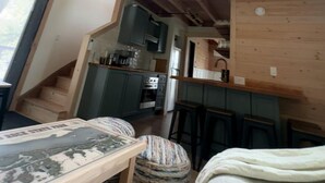 A loft-style bedroom with a wooden ceiling, a small window, and a bed.