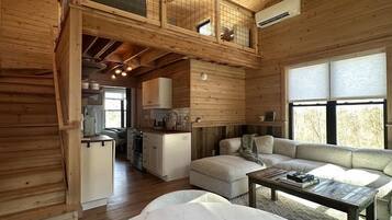 A spacious loft-style room with a high ceiling, a ceiling fan, a dining area, and a cozy seating area.