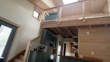 Une chambre de style « loft », avec un plafond en bois, une petite fenêtre et un lit.