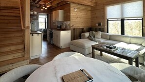A spacious loft-style room with a high ceiling, a ceiling fan, a dining area, and a cozy seating area.