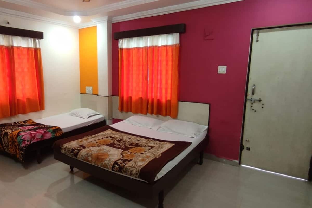 Una habitación con dos camas individuales, televisión, una silla roja y una puerta.