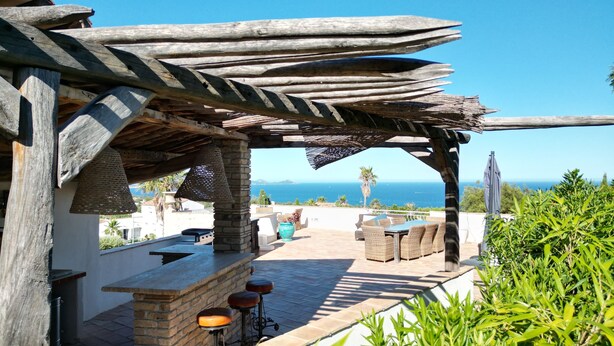 An outdoor patio with a pergola, stone bar, seating, and a view of the sea. - Villa Boucheron - 4 independent apartments - Sea view (Roquebrune-sur-Argens)