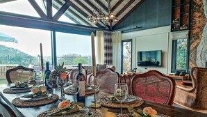 Een eethoek met een lange tafel gedekt voor een maaltijd, een televisie en een prachtig uitzicht.
