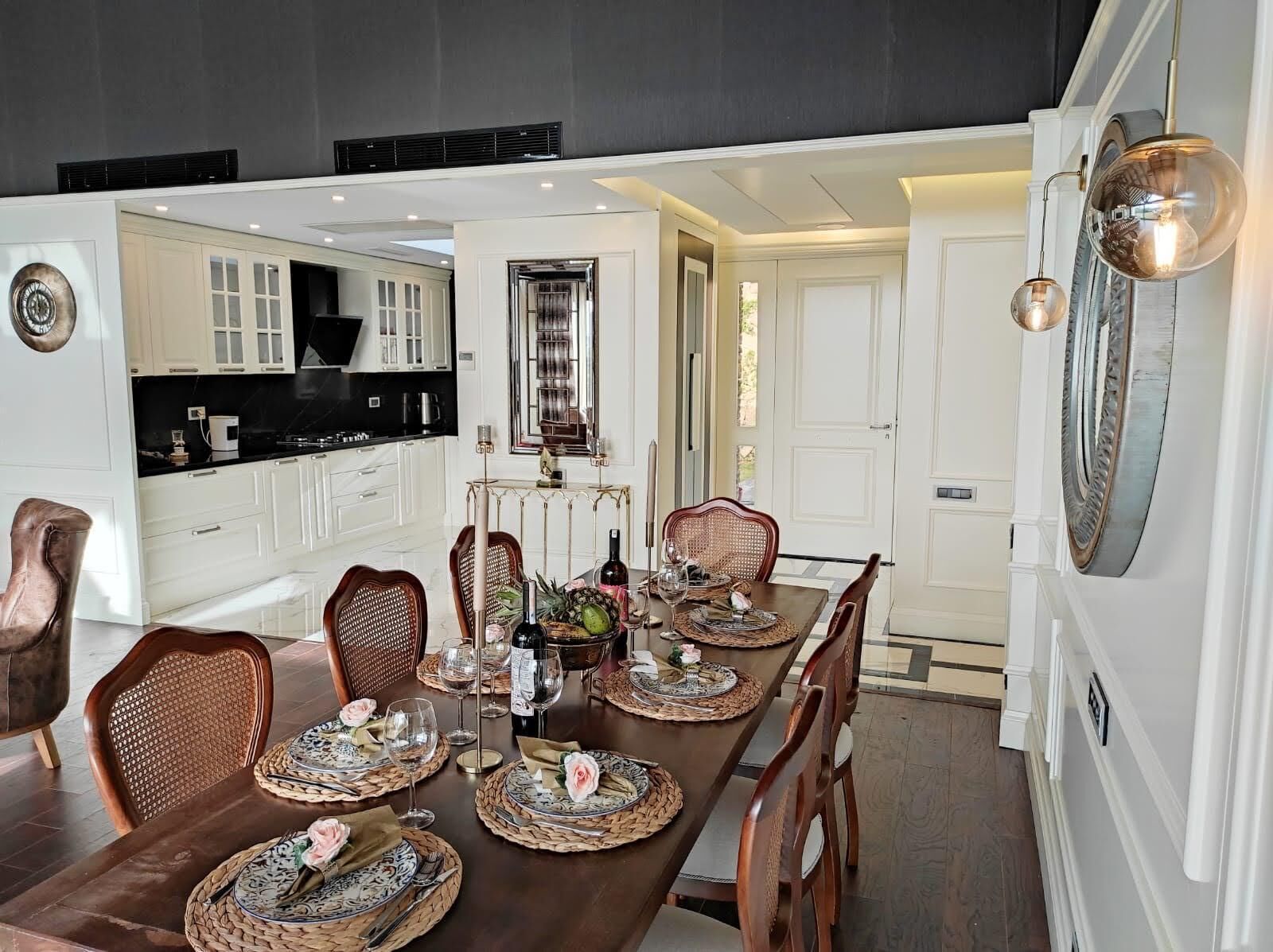 A dining area with a long table set for six, surrounded by wicker chairs.