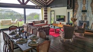 Een ruime woonkamer met een eettafel gedekt voor een maaltijd, een bank en een open haard.