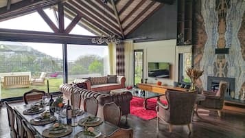 Amplia sala de estar con una mesa de comedor dispuesta para una comida, un sofá y una chimenea.